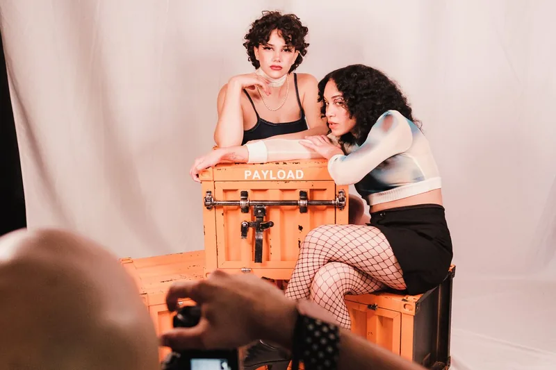 Photographer framing a studio portrait session with two models