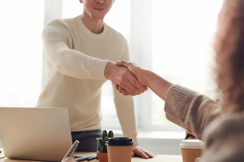 Professional welcoming a client with a handshake across a desk